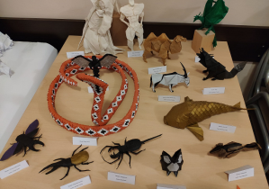 Wystawa prac wykonanych techniką origami przedstawiająca różne bryły i figury zwierząt, postaci z bajek.